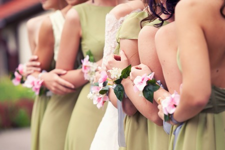 bride and bridesmaids in green dresses and flower bracelets on handsの写真素材