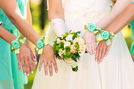bride with a bouquet and bridesmaids in green dresses and bracelets on handsの写真素材