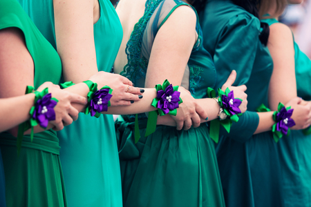 bridesmaids in green dresses with violet bracelets on handsの写真素材