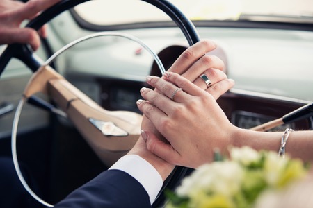 hands of the groom and the bride on a wheel of retro carsの写真素材