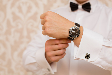 expensive watch at the groom in a suit
