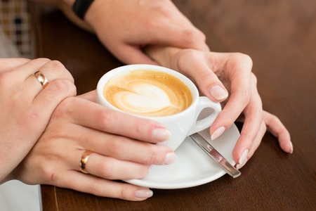 hands of the groom and the bride hold a cup of coffeeの写真素材