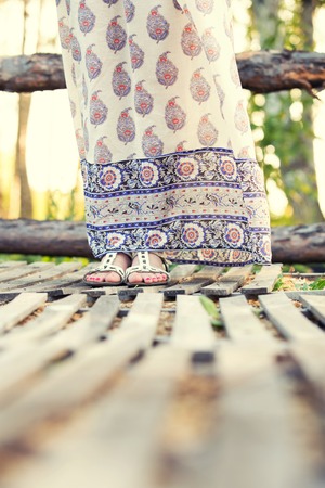 the girl's feet in a beautiful Russian sundress on the wooden bridgeの写真素材