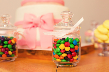 Colorful candies in jar on table and wedding cakeの写真素材