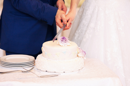 beautiful newlyweds cutting stylish cake with flowers, celebrating weddingの写真素材