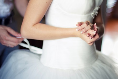 Bridesmaid is helping the bride to dressの写真素材