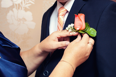hands of mother correct a buttonhole for the groomの写真素材