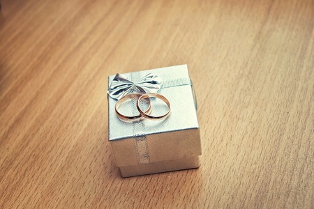 Gold ring in silver gift box on wooden background