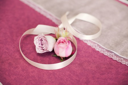 buds of a rose and beige tape on a claret background. Wedding attributes