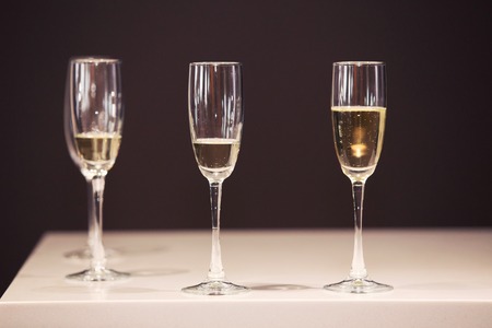 Three glasses of champagne waiting to be served by guests in a restaurantの写真素材
