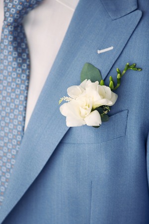 The groom in a blue suit with a bow tie and buttonhole on the lapel of his jacket.の写真素材