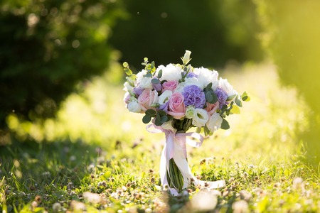 Beautiful bridal bouquet at sunset on wooden bridgeの写真素材