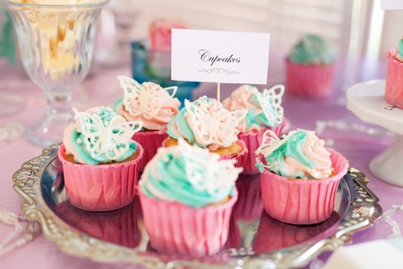 colorful capcakes with butterflies on a holiday tableの写真素材