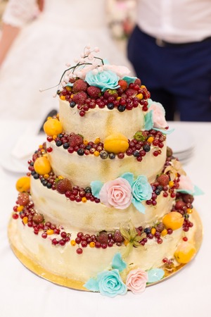 newlyweds cut wedding cake with fruitの写真素材