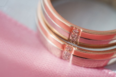 Wedding gold rings on a pink ribbon. Gold and platinumの写真素材