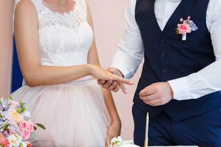 Groom putting a ring on brides finger during wedding ceremonyの写真素材