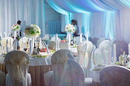 Restaurant hall full of white fabric and round tables in blueの写真素材