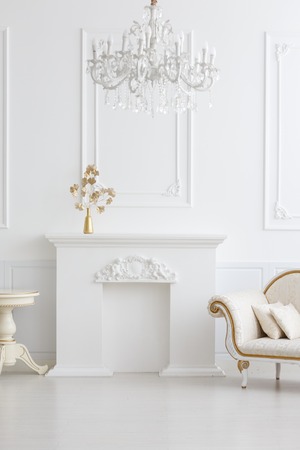 beautiful classical white interior with a fireplace, a sofa and a vintage chandelier. Retro, classicsの写真素材