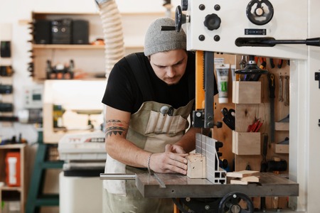 profession, carpentry, woodwork and people concept - carpenter working with plane and wood plank at...
