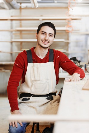 Portrait of a worker in work clothes in front of workbench tools / Portrait of man at work in workshop in garage at home. Craftsman makes own successful small business.の写真素材