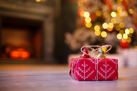 Gift boxes with gold and red Jingle Bells against a bokeh of twinkling party lights. Luxury New Year gift. Christmas gift. Christmas with gift box. Christmastime celebrationの写真素材