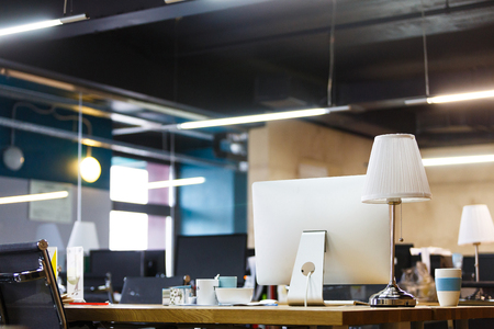 Business concept. An empty office is waiting for employees. Wooden table with computers, lamps, coffee mugs and stationery. Co-workingの写真素材