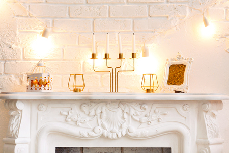 A traditional bright Christmas decoration on a fireplace with candles, on a white brick wall with bright burning garlands.Christmas concept, new year.の写真素材