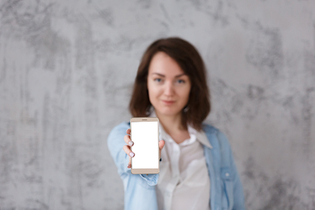 Beautiful blurred young woman holding smartphoneの写真素材
