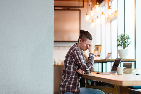 Side view - young tired man manager of large firm - sitting at the computer tired of headache. Difficult life in the big cityの写真素材