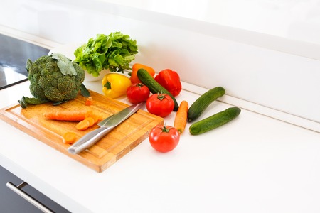 Vegetarian menu. Multicolored healthy vegetables - broccoli, Bulgarian pepper and tomatoes with cucumber lie next to the cutting board and knifeの写真素材