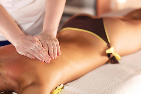 Hands of an unidentified female masseuse doing massage for an unknown young girl lying on a massage table in spa salon.Spa body massage treatment.の写真素材