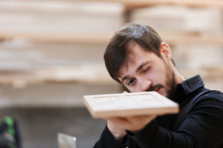 Carpenter looking carefully at a new product made from wood in preparation for entrepreneurial marketingの写真素材