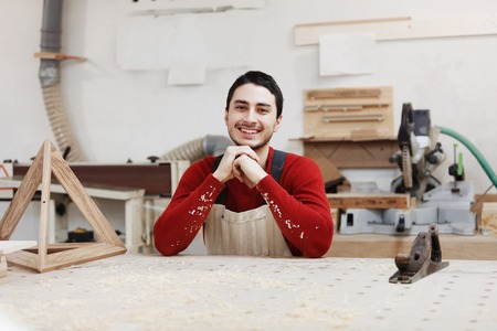 Portrait of a worker in work clothes in front of workbench tools / Portrait of man at work in workshop in garage at home. Place for the text.の写真素材