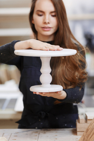 Portrait of cheerful young woman working in carpenters shop. Family business. startup business. young specialist designer.の写真素材