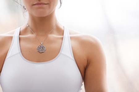 Close-up slim, tight body of  young girl in light suit sitting in  lotus pose while doing yogaの写真素材
