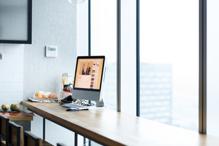 Empty workplace. Laptop, smartphone and tablet lie on wooden table on the background of large window overlooking the big skyscrapers in the business center. Copyspaceの写真素材