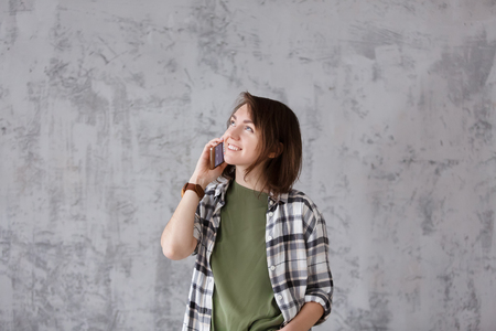 Portrait of positive beautiful girl talking on smartphone on gray background. Copyspaceの写真素材