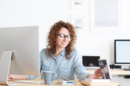 Portrait of female freelancer or female copywriter works alone, writes notes,surfing high-speed internet on laptop pc in creative designer studioの写真素材