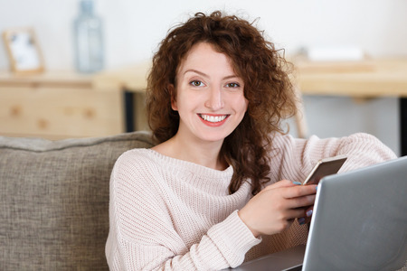 Beautiful red hair caucasian woman chats on cell phone after working day, types message, uses modern technologies for work and communication, surfes social networksの写真素材