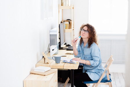 Portrait of attractive young female architect looking up, having dreamy facial expression while working on new construction projectの写真素材
