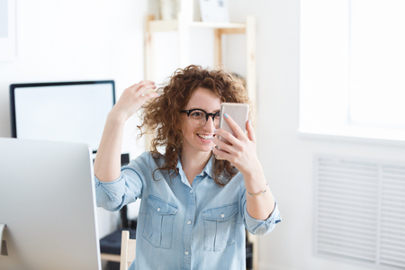 Young charming employee of the company have fun, make selfie with modern cell phone, have happy expressions during a break at work Ñin office. People, technology conceptの写真素材