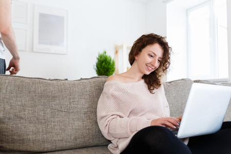 Happy female copywriter writes ideas on laptop, uses computer for creating new article in fashion magazine.の写真素材