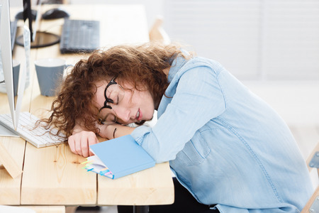 Overworked female student sleeping while making homework assignment all night, sitting at deskÑ Stress, fatigue overwork.の写真素材
