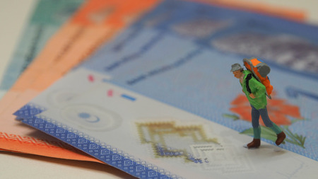 Miniature figure of backpacker walks on the Malaysian banknotesの写真素材