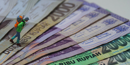 Miniature figure of backpacker walks on the Malaysian banknotesの写真素材