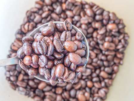 Close up Coffee beans with a spoon to scoop stainless steel.の写真素材