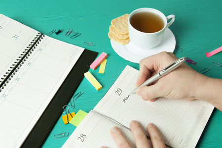 Workplace with organizer, pen, pencil, crackers and cup of teaの写真素材
