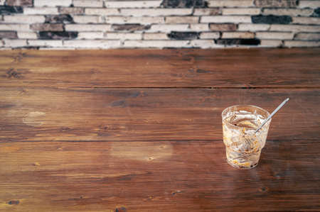An empty dessert profiterole cup with spoon on a brown wooden table after eatenの写真素材