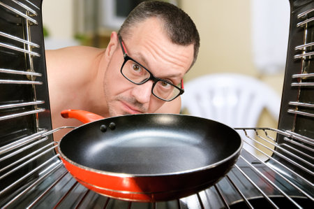 Concept of cooking by men, looking at oven for preparing food. Men cooking at home. View from inside