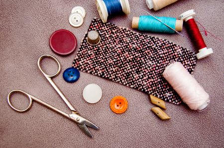 Colorful bobbins, buttons, a fabric and a scissor for sewingの写真素材
